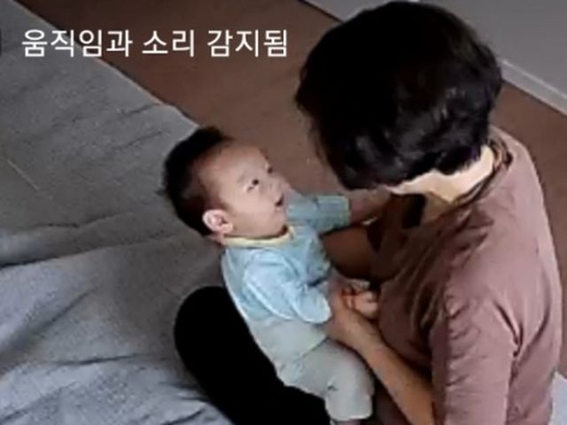 홈캠 화면에 비친, 관리사와 함께 있는 아기